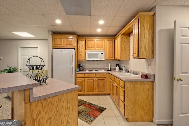 kitchen featuring a paneled ceiling, white appliances, sink, and light tile patterned floors