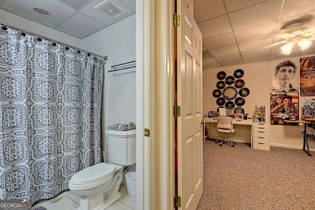 bathroom featuring tile patterned floors, a drop ceiling, and toilet