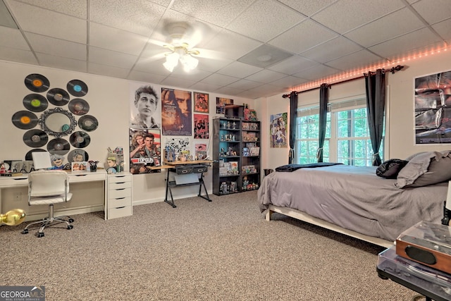 carpeted bedroom with a paneled ceiling and ceiling fan