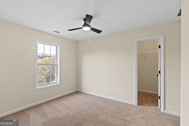 unfurnished bedroom with carpet, a spacious closet, visible vents, and baseboards