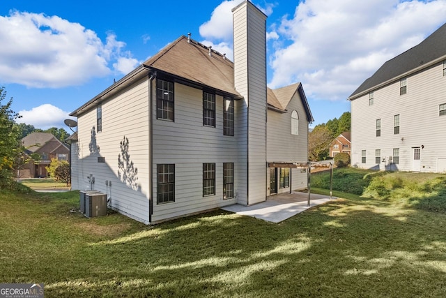 back of house featuring a patio area, a chimney, central AC unit, and a lawn