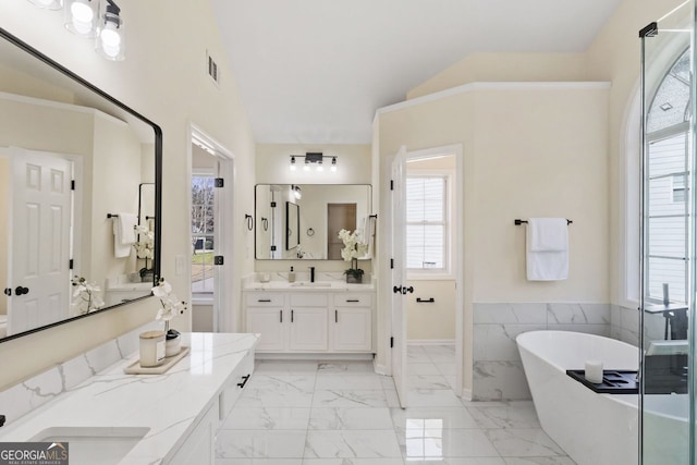 full bath with marble finish floor, visible vents, vaulted ceiling, vanity, and a freestanding tub