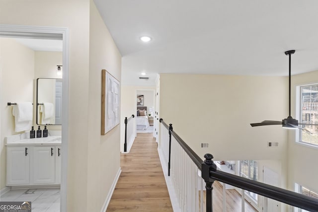 corridor featuring baseboards, an upstairs landing, visible vents, and recessed lighting