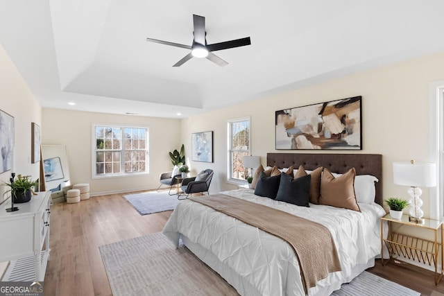 bedroom with ceiling fan, recessed lighting, baseboards, light wood-style floors, and a raised ceiling