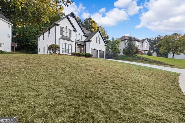 tudor-style house featuring a garage and a front lawn