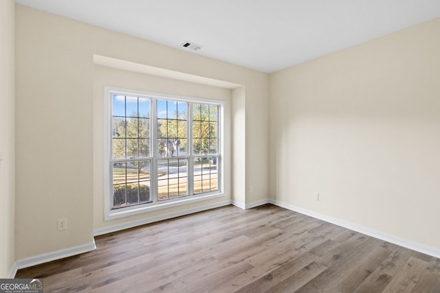 unfurnished room with visible vents, baseboards, and wood finished floors