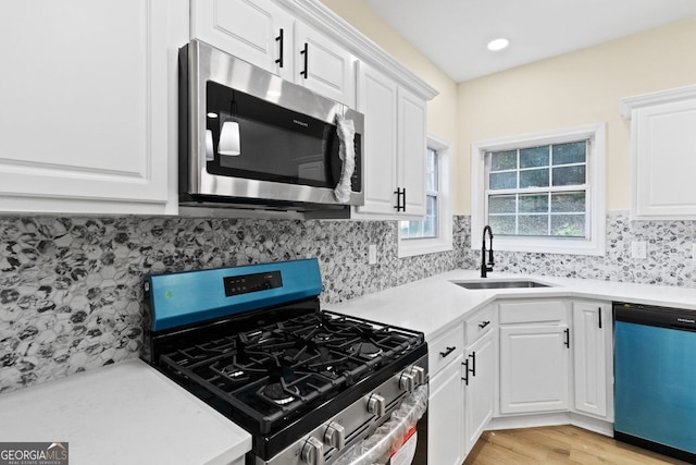 kitchen with tasteful backsplash, appliances with stainless steel finishes, white cabinets, and a sink