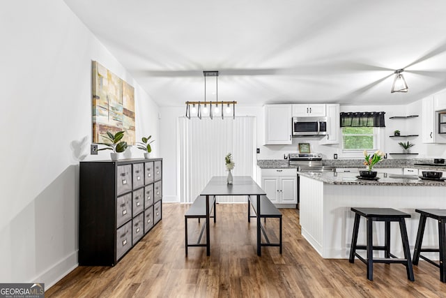 kitchen featuring hardwood / wood-style floors, appliances with stainless steel finishes, and white cabinetry