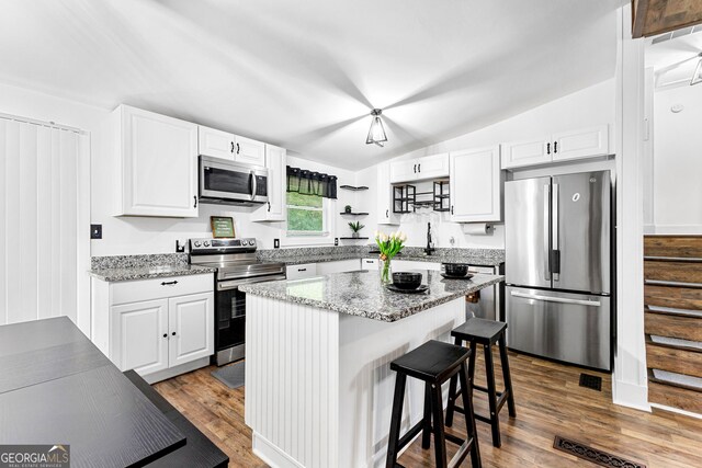 kitchen with a center island, lofted ceiling, stainless steel appliances, and dark hardwood / wood-style floors