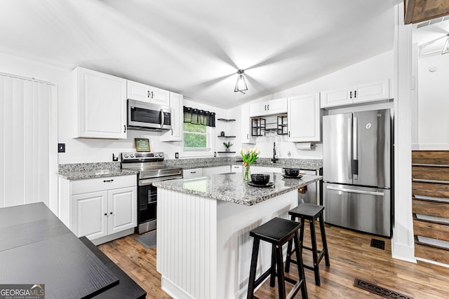 kitchen featuring dark wood finished floors, vaulted ceiling, white cabinets, and appliances with stainless steel finishes