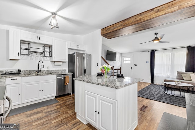 kitchen featuring dark wood-style flooring, a sink, appliances with stainless steel finishes, white cabinetry, and open floor plan