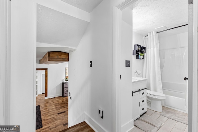 full bathroom with vanity, shower / bathtub combination with curtain, wood finished floors, a textured ceiling, and toilet