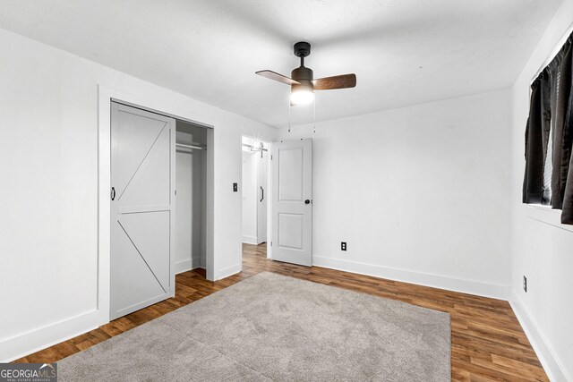 unfurnished bedroom featuring wood-type flooring, ceiling fan, and a closet