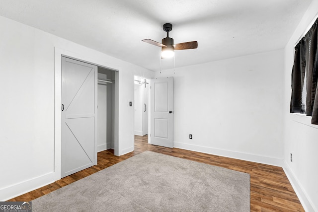 unfurnished bedroom featuring a closet, baseboards, wood finished floors, and a ceiling fan