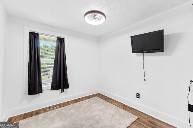 empty room with a textured ceiling and hardwood / wood-style floors