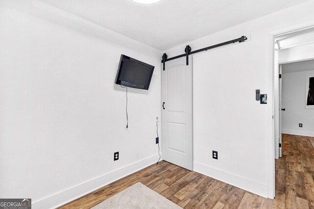 bedroom with a barn door and hardwood / wood-style floors