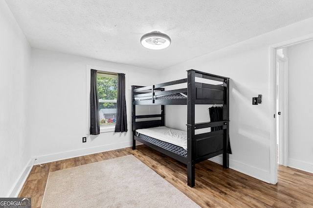 bedroom with a textured ceiling and wood-type flooring