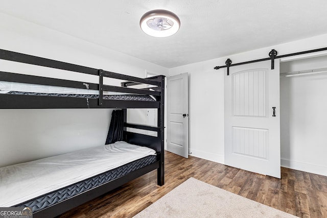 bedroom featuring a barn door, wood finished floors, and baseboards