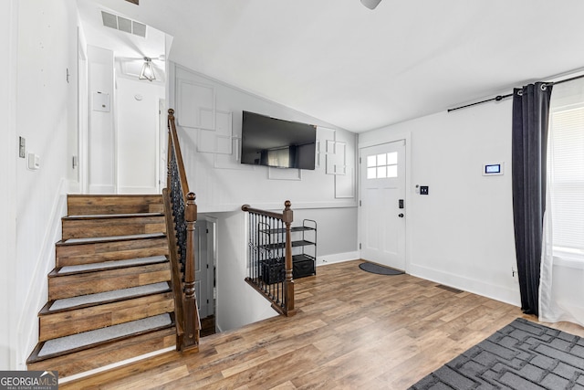 entrance foyer with stairway, wood finished floors, visible vents, and baseboards