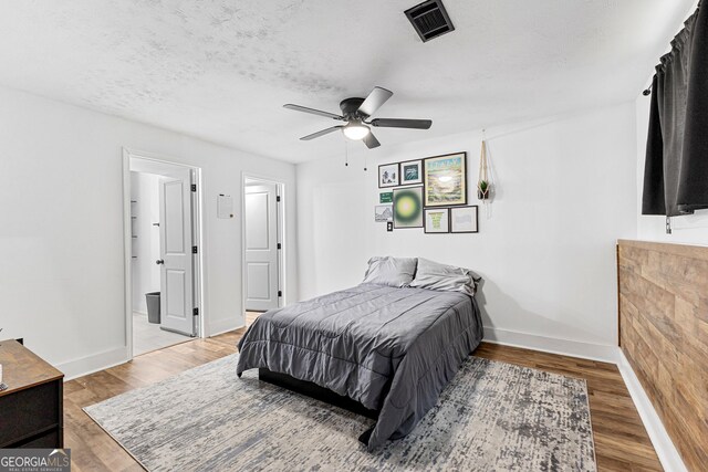 bedroom with light wood-type flooring, a textured ceiling, and ceiling fan