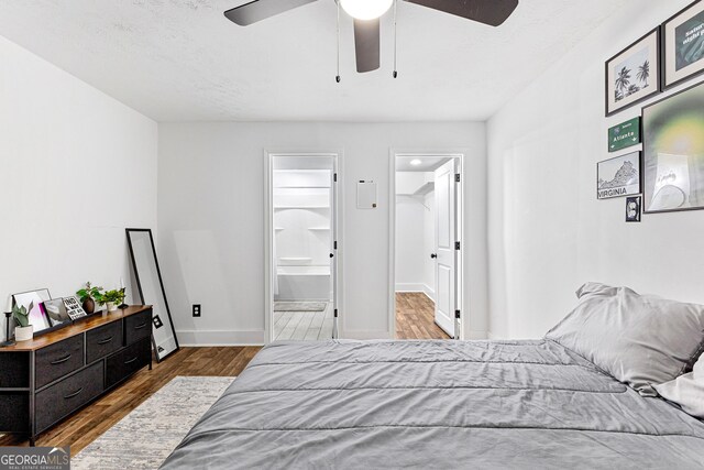 bedroom with wood-type flooring, a walk in closet, ensuite bathroom, and ceiling fan