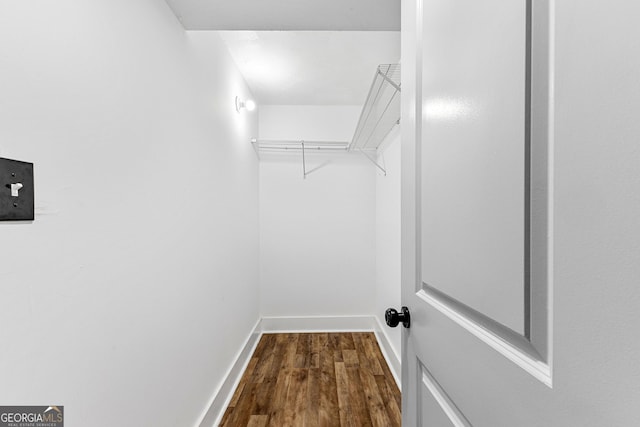 walk in closet with dark wood-style floors