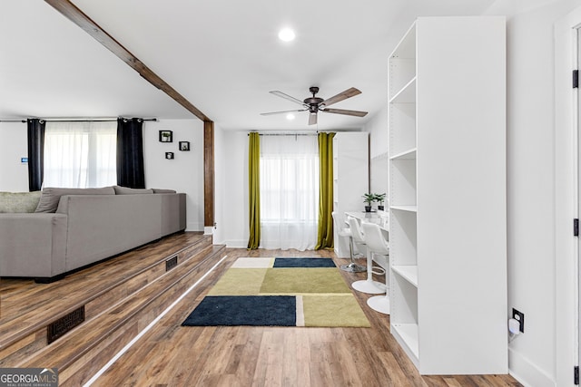 living room with visible vents, baseboards, wood finished floors, and a ceiling fan