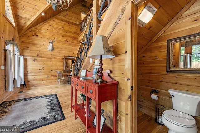 bathroom featuring wood walls, wood ceiling, lofted ceiling with beams, toilet, and hardwood / wood-style flooring