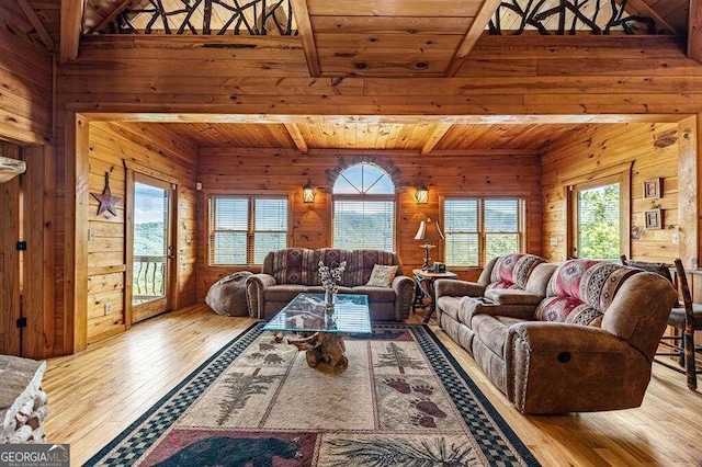 living room with beam ceiling, wooden walls, light hardwood / wood-style floors, and wooden ceiling