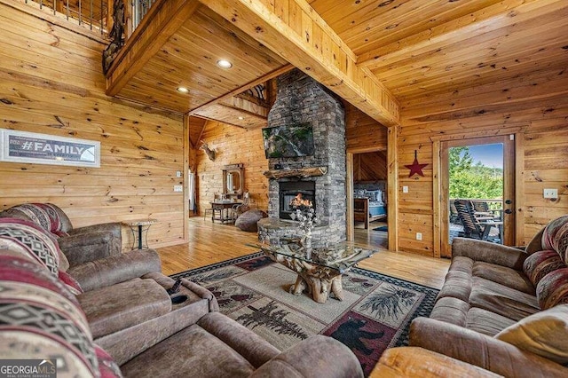 living room with wood ceiling, wood-type flooring, a fireplace, a towering ceiling, and wood walls