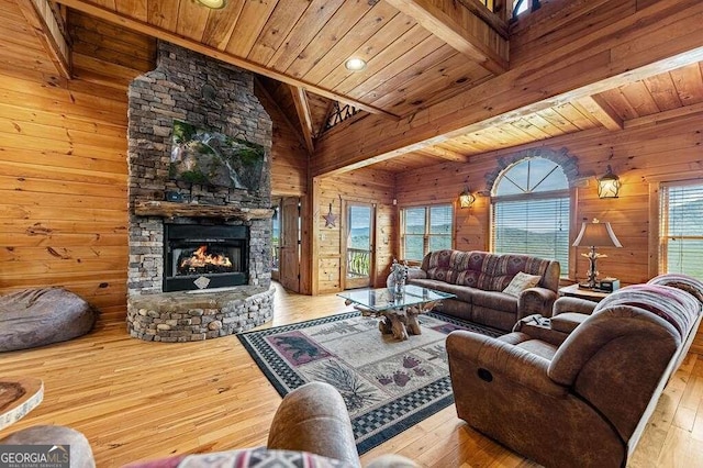 living room with light wood-type flooring, a fireplace, lofted ceiling with beams, wooden ceiling, and wooden walls