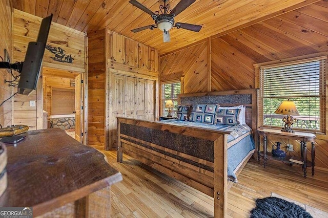 bedroom with ceiling fan, wood ceiling, light hardwood / wood-style floors, and wood walls