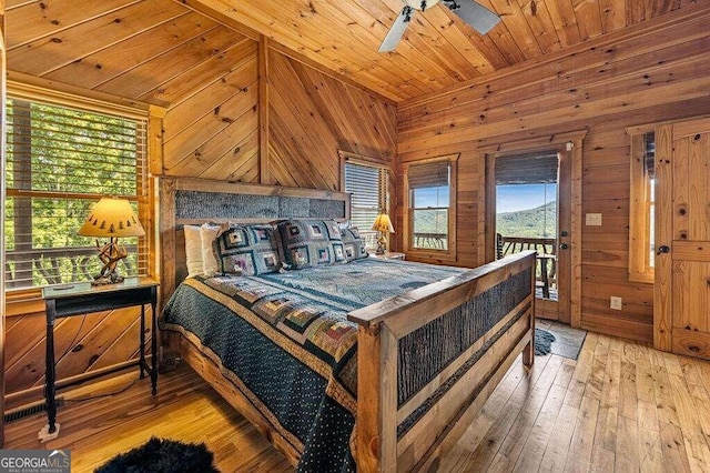 bedroom with light hardwood / wood-style floors, wood walls, wood ceiling, and ceiling fan