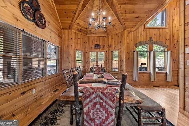 dining room featuring light hardwood / wood-style floors, a notable chandelier, wooden ceiling, and wooden walls