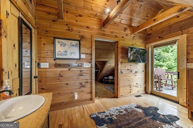 bathroom with wood walls, wood-type flooring, sink, wood ceiling, and beam ceiling