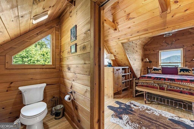 bathroom with toilet, lofted ceiling, wooden walls, and wood-type flooring