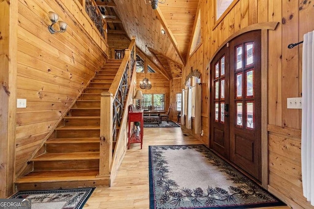 entrance foyer featuring wood ceiling, high vaulted ceiling, light hardwood / wood-style floors, and wood walls