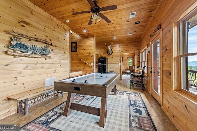 game room with wood ceiling, wood walls, light tile patterned floors, and ceiling fan