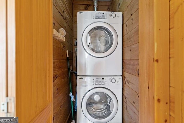 clothes washing area with stacked washer / dryer and wood walls