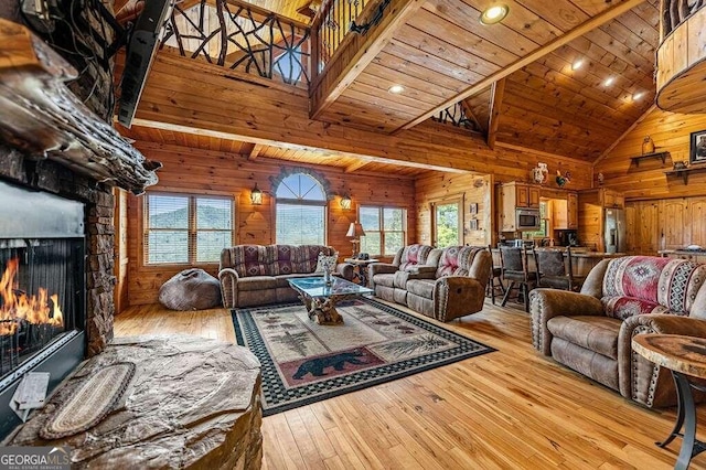 living room with a stone fireplace, wood ceiling, wooden walls, light wood-type flooring, and high vaulted ceiling