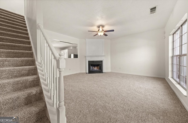 unfurnished living room featuring a textured ceiling, ceiling fan, and carpet flooring