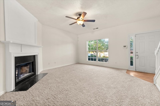 unfurnished living room featuring a textured ceiling, ceiling fan, and hardwood / wood-style floors