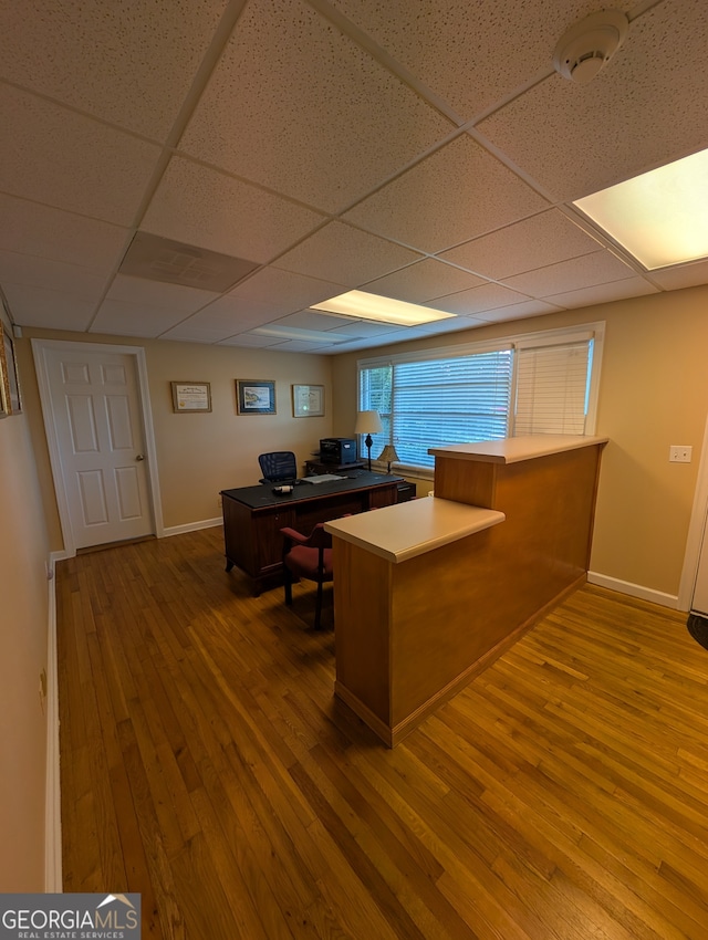 interior space with hardwood / wood-style flooring, kitchen peninsula, and a drop ceiling