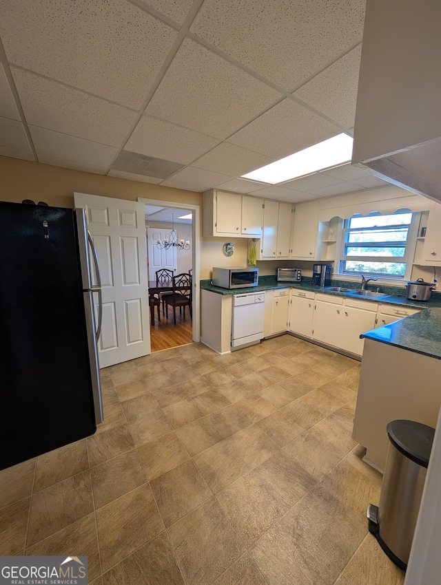 kitchen featuring appliances with stainless steel finishes, white cabinetry, sink, and a drop ceiling