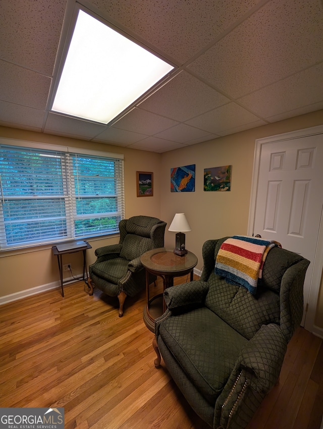 living room featuring wood-type flooring and a paneled ceiling