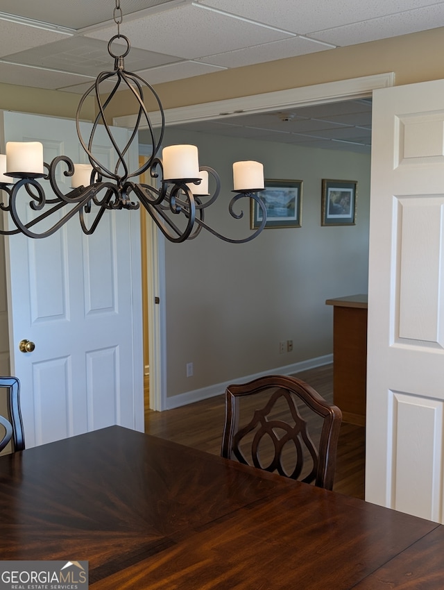 unfurnished dining area with a paneled ceiling and wood-type flooring