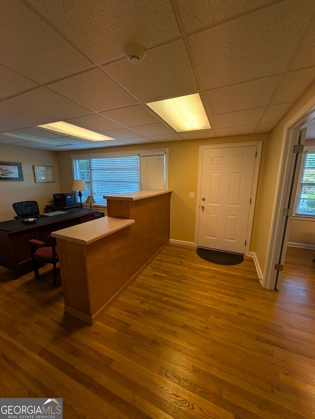 unfurnished office with hardwood / wood-style floors and a paneled ceiling