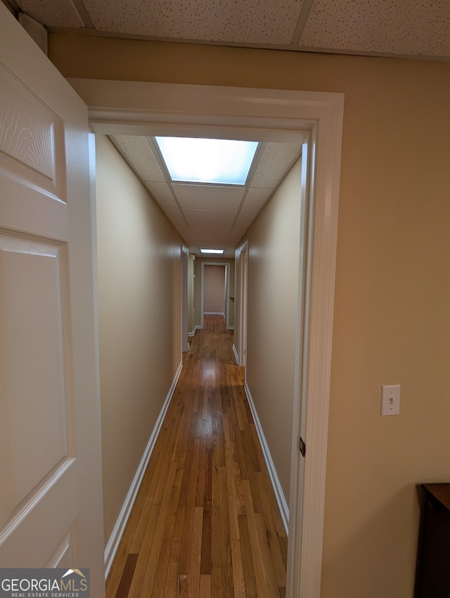 hallway with light hardwood / wood-style flooring and a drop ceiling