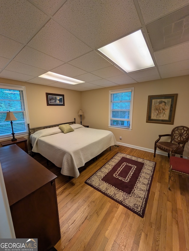 bedroom with a paneled ceiling and wood-type flooring