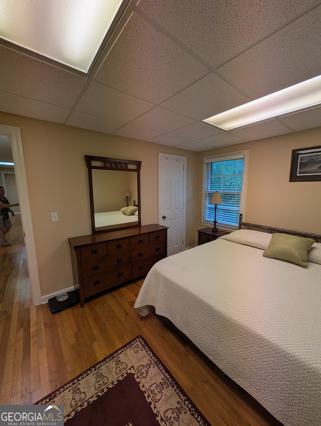 bedroom with hardwood / wood-style floors and a drop ceiling